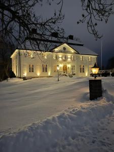 NäsvikenForsså Herrgård hotell och SPA的白色的建筑,晚上有雪灯