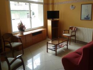 格罗韦帕拉伊索玛丽索酒店的客厅配有电视、椅子和桌子