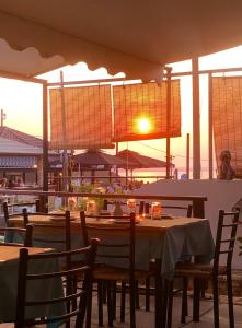 波帝卡Thaleia view的餐厅设有桌椅,享有日落美景