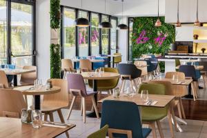 维特罗勒金色郁金香马赛机场酒店的餐厅设有桌椅和窗户。