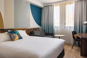 维特罗勒金色郁金香马赛机场酒店的配有一张床和一张书桌的酒店客房
