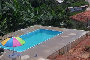 卡舒埃拉坎普Sítio da Serra em Ouro Preto MG的游泳池旁配有五颜六色的遮阳伞