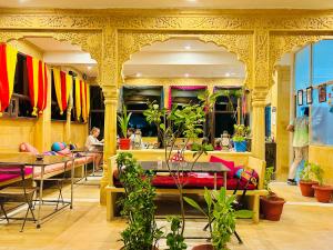 斋沙默尔Hotel Pol Haveli Jaisalmer的餐厅设有桌椅,背景人员