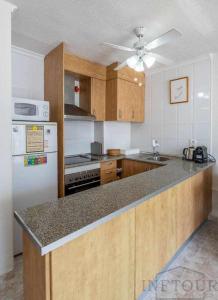 卡尔佩Inftour Atlanta 14 Apartamento的厨房配有木制橱柜和白色冰箱。