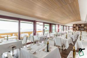 利沃诺HOTIDAY Hotel Livorno的餐厅设有白色的桌椅和窗户。