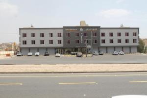 Al Maraghahداماس للأجنحة الفندقية Damas Hotel Suites的停车场内停放汽车的大型建筑
