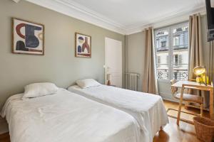 巴黎Hôtel Juliette的一间卧室设有两张床、一张桌子和一个窗口
