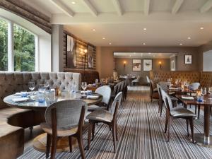 沃尔斯雷Delta Hotels by Marriott Worsley Park Country Club的餐厅设有桌椅和沙发。