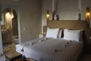 马拉喀什安贝瑞扎哈里摩洛哥传统庭院住宅的卧室配有一张白色大床,上面有鸟儿