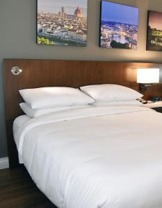 印第安纳波利斯Delta Hotels by Marriott Indianapolis East的卧室配有一张白色床,墙上挂有两张照片