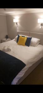 OffleyThe Red Lion Great Offley的一张带两个枕头和黄色枕头的白色床