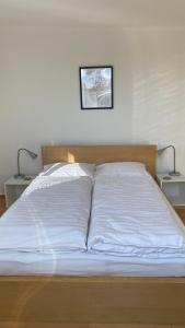 克拉根福Wohnung am Spitalberg的一张带白色床单的床和两张桌子上的两盏灯