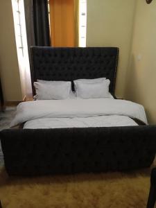 MeruCeeJ'S Airbnb的卧室内的一张大床和黑色床头板