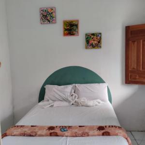 Caeté-AçuJoão de Barro Hospedagem的一张带绿色床头板的床和墙上的三张照片