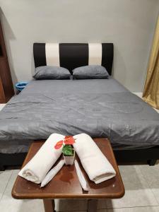 怡保Galaxy Guest Home by Ipoh Maju Stay的一张带两张白色毛巾的木桌床