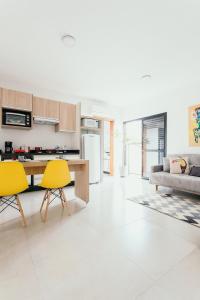 波苏斯-迪卡尔达斯Apartamentos modernos e aconchegantes no centro.的厨房以及带黄色椅子和桌子的客厅