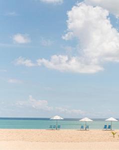 福塔莱萨Netuno Beach Hotel的海滩上的三把椅子和遮阳伞
