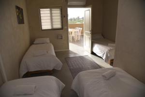 Shadmot Devoraחאן דרך העץ - חדרי מטיילים的客房设有三张床和一个带桌子的窗户