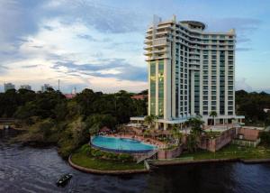 马瑙斯Hotel Tropical Executive Flat 918的一座大型建筑,设有游泳池,毗邻河流
