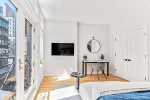 纽约Studio w Charming Juliet Balcony in Upper East的白色卧室配有床和书桌