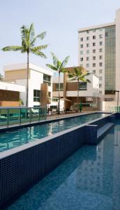 巴西利亚Jade Hotel Brasília的棕榈树建筑前的游泳池