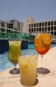 巴西利亚Jade Hotel Brasília的坐在游泳池旁的桌子上喝三杯饮料