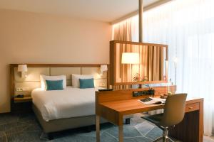 马斯特里赫特马斯特里赫特皇冠假日酒店的酒店客房配有一张床、一张书桌和一张书桌。