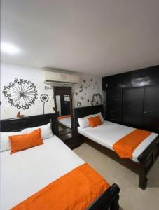 AracatacaCasa Turística Realismo Mágico的一间卧室配有两张带橙色和白色床单的床