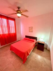 普拉亚斯Casa con piscina y salida a la playa的一间卧室配有红色的床和吊扇