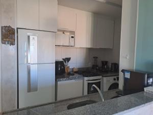 卡姆布库VG Sun Cumbuco 406的厨房配有白色橱柜和冰箱。