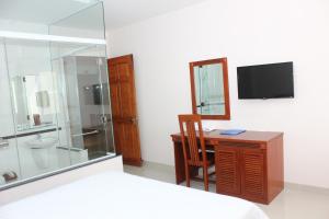 波来古市黄玉酒店的一间卧室配有书桌、淋浴和电视