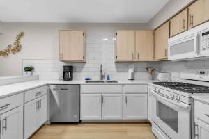 布法罗Downtown & Upscale的白色的厨房配有白色家电和木制橱柜