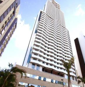 萨尔瓦多Apartamento Mondial Salvador的一座高大的建筑,前面有棕榈树