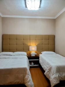 碧瑶Kaias Transient & Condotels - 539 Albergo的一间卧室配有两张床和一张带台灯的桌子