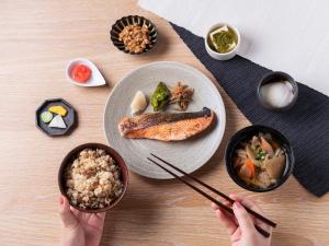 东京千禧 三井花园饭店 东京 / 银座的一张桌子,上面有盘子食物,还有人拿着筷子