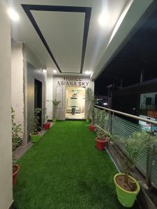 艾哈迈达巴德HOTEL ASIANA SKY Motera Ahmedabad的绿草成荫的建筑里的一个走廊