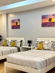 公主港D' Beach Resort的白色客房的两张床,墙上挂有绘画作品