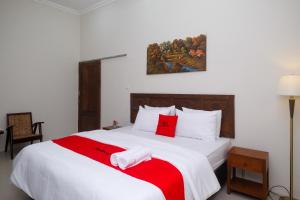 KlatenRedDoorz Syariah near Stasiun Klaten的卧室配有带红色枕头的大型白色床