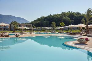 科孚镇Ikos Odisia的度假村的游泳池,提供蓝色的水和遮阳伞