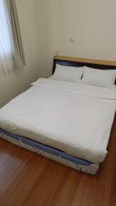 Xiulin太鲁阁峡林咖啡农庄的铺有木地板的一张带白色床单和枕头的床