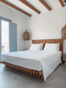 斯希努萨岛Sohoros Luxury Suites的卧室配有一张白色大床和木制床头板