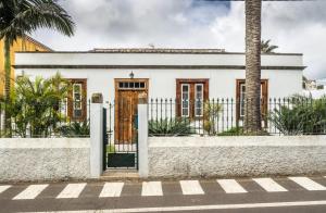 拉拉古纳Donde Conchita, buhardilla con baño compartido, cerca del aeropuerto norte的一座白色的房子,有门和棕榈树