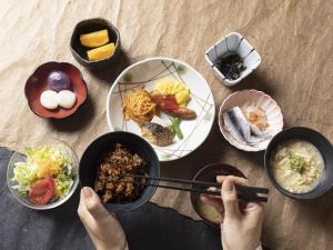 冈山冈山三井花园酒店 的把筷子放在餐桌上,放上食物盘的人