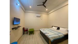 瓦拉纳西Srinivasan Villa的一间卧室配有一张床、一台电视和一把椅子