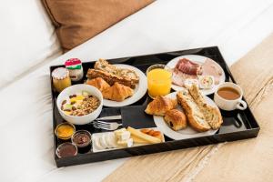 巴黎Maison Pigalle的床上装满早餐食品的托盘