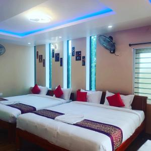 KottakupamParadise Breeze Inn的配有红色和白色枕头的客房内的两张床
