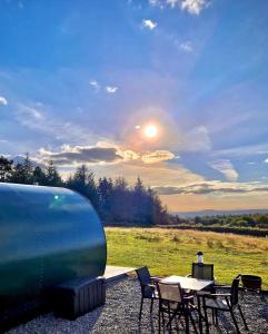 BallintleaForth Mountain Glamping的野餐桌和椅子,太阳在天空中