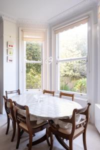 伦敦Veeve - Courtside Charms的一间带桌子和2个窗户的用餐室
