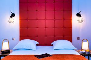 恩尼瑞绿色印象派公寓式酒店的卧室里红色的软垫床头板,配有两盏灯