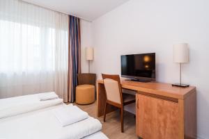 多特蒙德G & L Hotel Dortmund的酒店客房配有一张书桌、一台电视和一张床